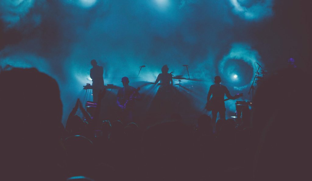 A live band performing onstage cast in blue stage lights.