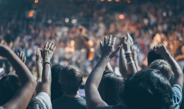 A crowd photograph of people with their arms outstretched