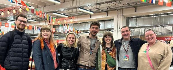 Tom Besford, members of Sounds Roots' Artist mentoring cohort and part of the Focus Wales team stand in a line posing for a photograph.